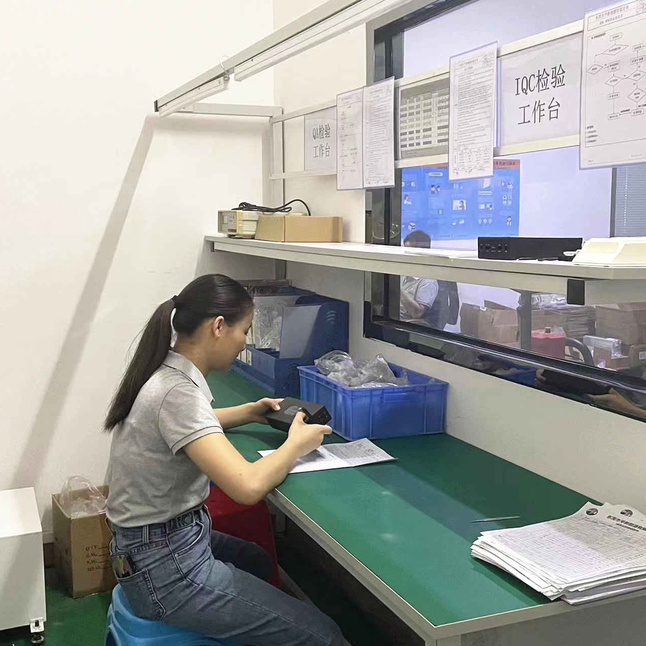 IQC inspection bench: inspector checking a unit against the inspection sheet